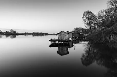 Paysage de l'étang du Welschhof en Moselle montrant des cabanes de pêcheurs et un rendu de gris doux