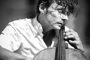 Photographie de rue d'un violoniste sous la lumière dure et contrastée d'un soleil de midi