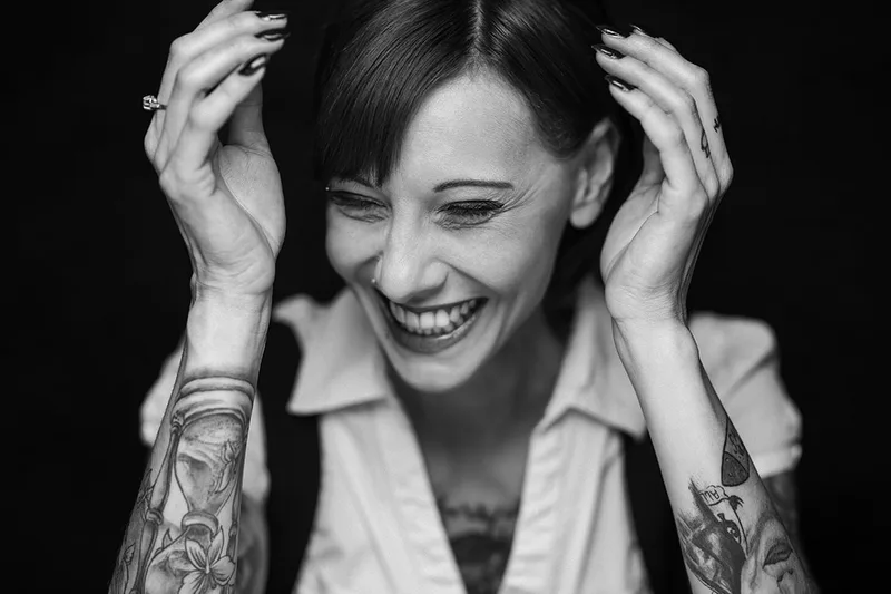 Portrait spontané d'une femme tatouée exprimant la joie et le rire, en Alsace