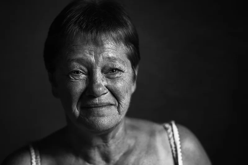 Portrait studio contrasté d'une femme mûre souriante aux rides d'expression