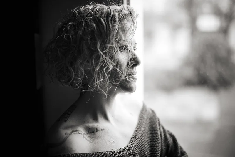Portrait intemporel d'une femme en lumière naturelle plongée dans ses pensées