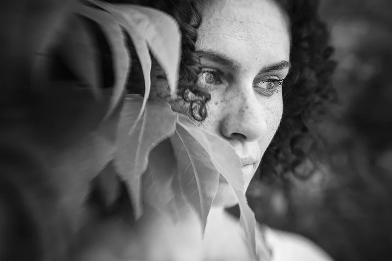 Portrait artistique d'une femme à travers le feuillage avec effet de flou Lensbaby