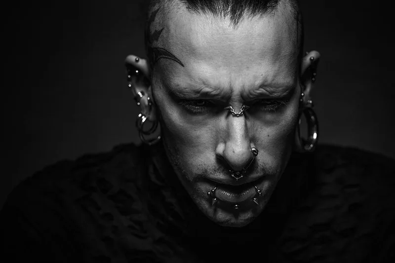 Portrait de caractère d'un homme arborant des tatouages et piercings gothiques
