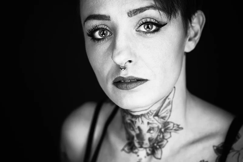 Portrait d'art en studio d'une femme mettant en avant ses tatouages et son regard
