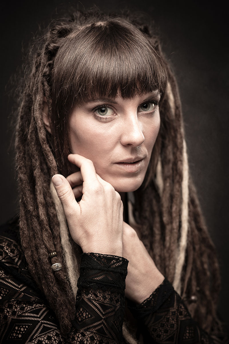 Portrait artistique en couleur d'une femme aux dreadlocks, regard expressif, réalisé en Belgique