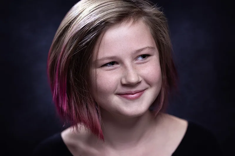 Portrait artistique en couleur d'une jeune fille souriante en studio