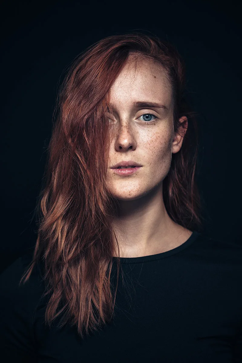 Portrait en studio d'une femme rousse dégageant un regard fort et déterminé