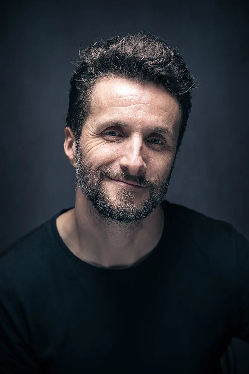 Portrait de communication d'un homme souriant dans une ambiance de studio bleue, à Sarreguemines