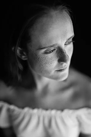 Portrait de femme en lumière naturelle exposé pour les hautes lumières, plongeant l'arrière-plan dans l'ombre