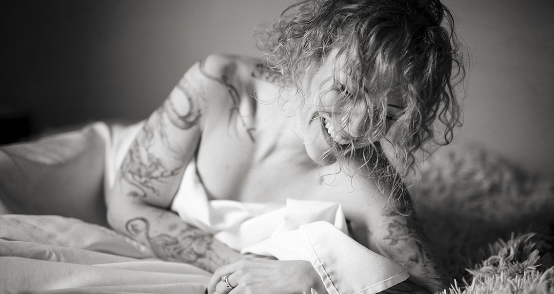 Portrait lumineux en noir et blanc d'une femme au sourire spontané, illustrant l'approche humaine et naturelle du photographe