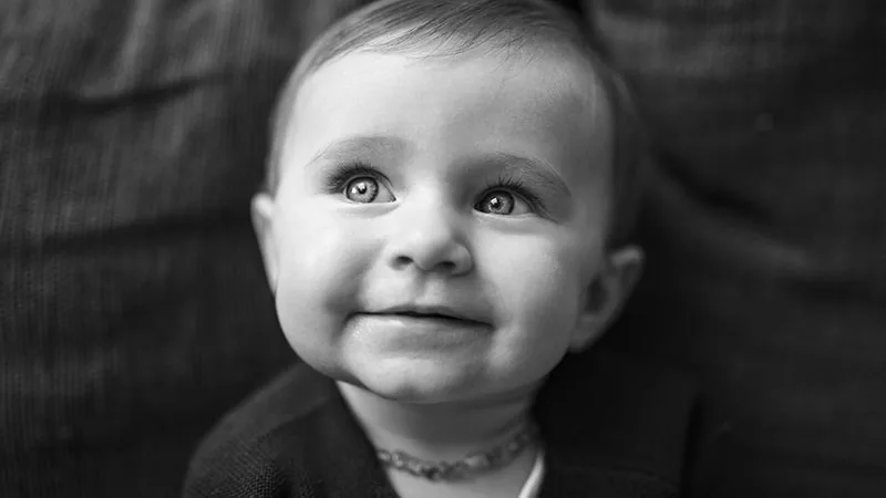 Portrait en noir et blanc d'un enfant souriant aux yeux clairs - Article : Le noir et blanc