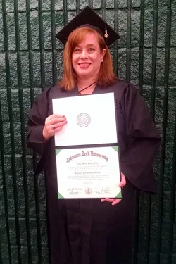 Dawn Marie posing with her 2014 diploma in her Arkansas Tech gown.