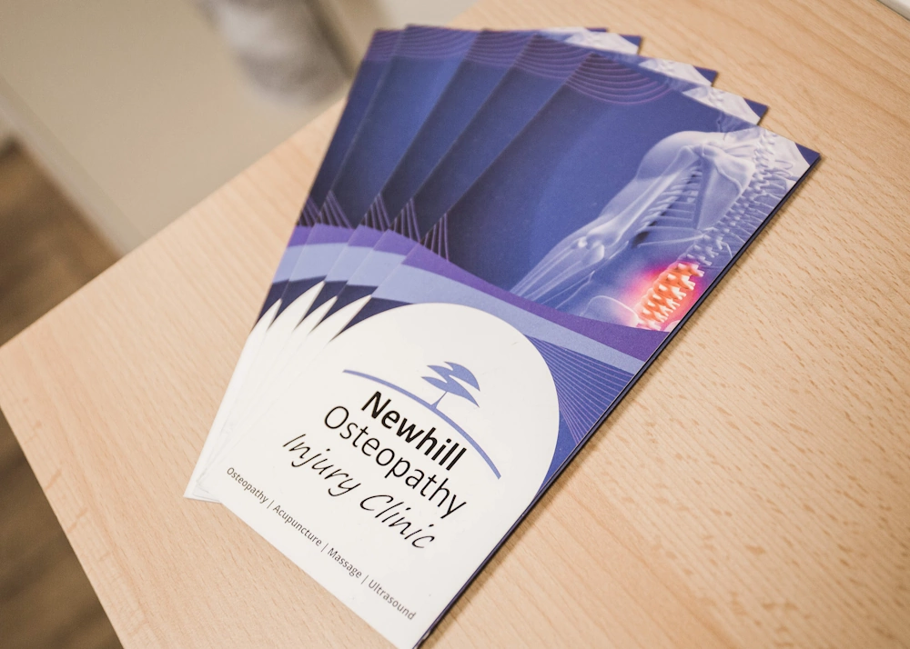 Tri fold leaflet for newhill osteopathy on a wooden table