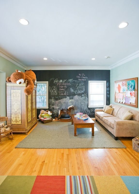 Kids' playroom design with chalkboard wall, cozy sofa and colorful rug
