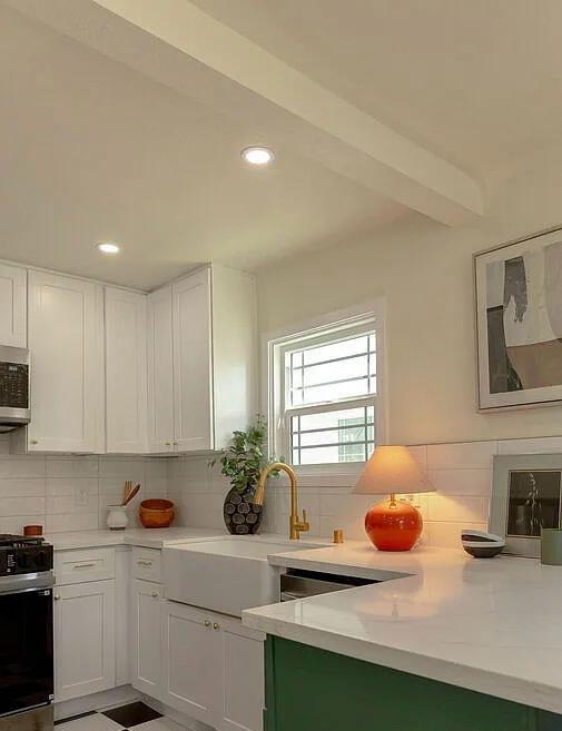 White kitchen with a green island and a farmhouse sink by Jill Seidner Interior Design