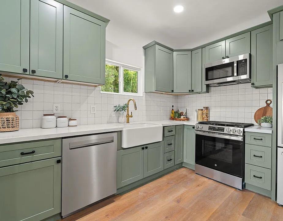 Kitchen with sage green cabinetry, white tile and a stainless range by Jill Seidner Interior Design