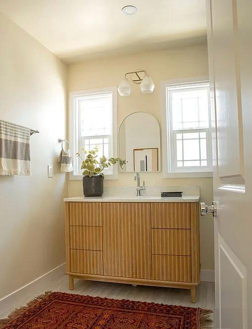 Bathroom with a fluted wood vanity and an arched mirror by Jill Seidner Interior Design