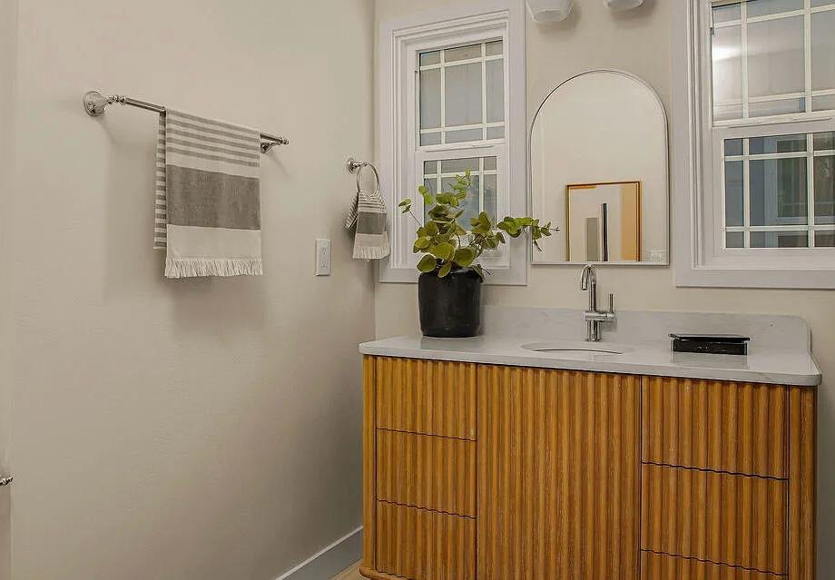 Bathroom with a fluted wood vanity and window by Jill Seidner Interior Design