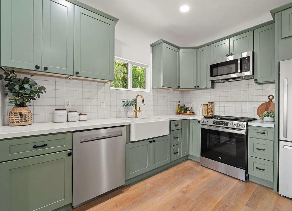 Sage green kitchen with a stainless range and white tile by Jill Seidner Interior Design
