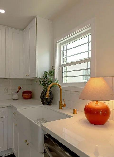White kitchen with a farmhouse sink and an orange lamp by Jill Seidner Interior Design