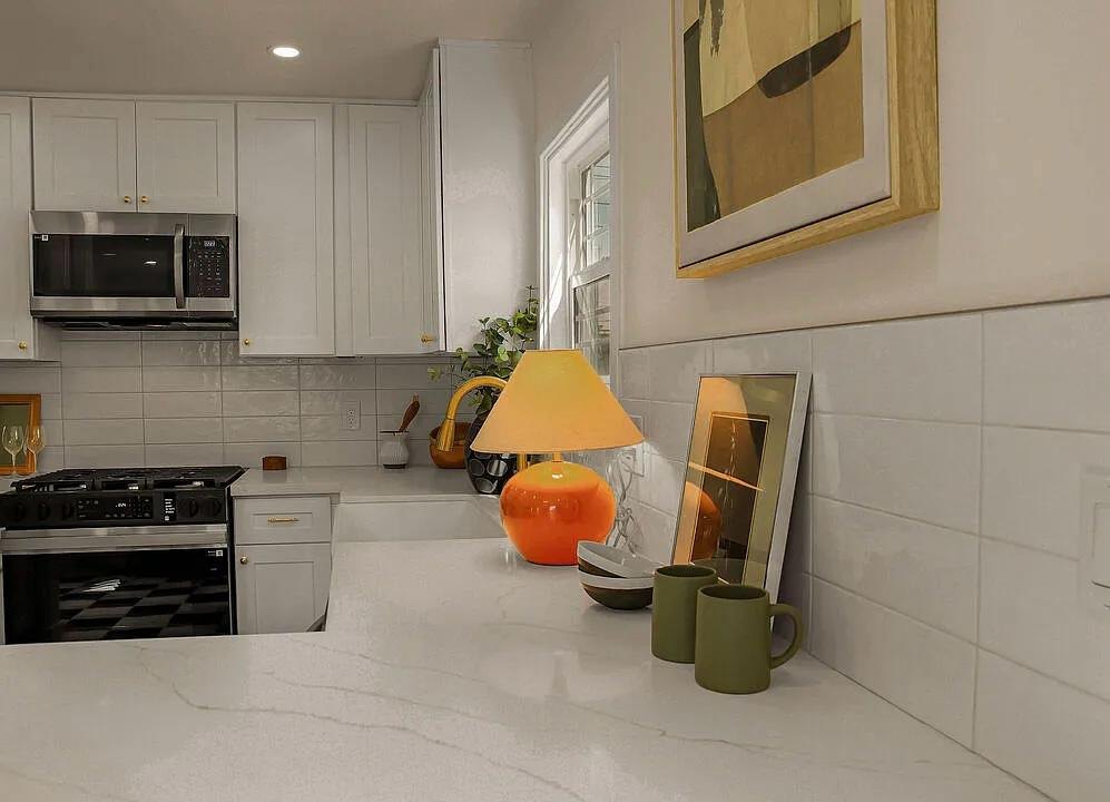 White kitchen counter with art and an orange lamp by Jill Seidner Interior Design