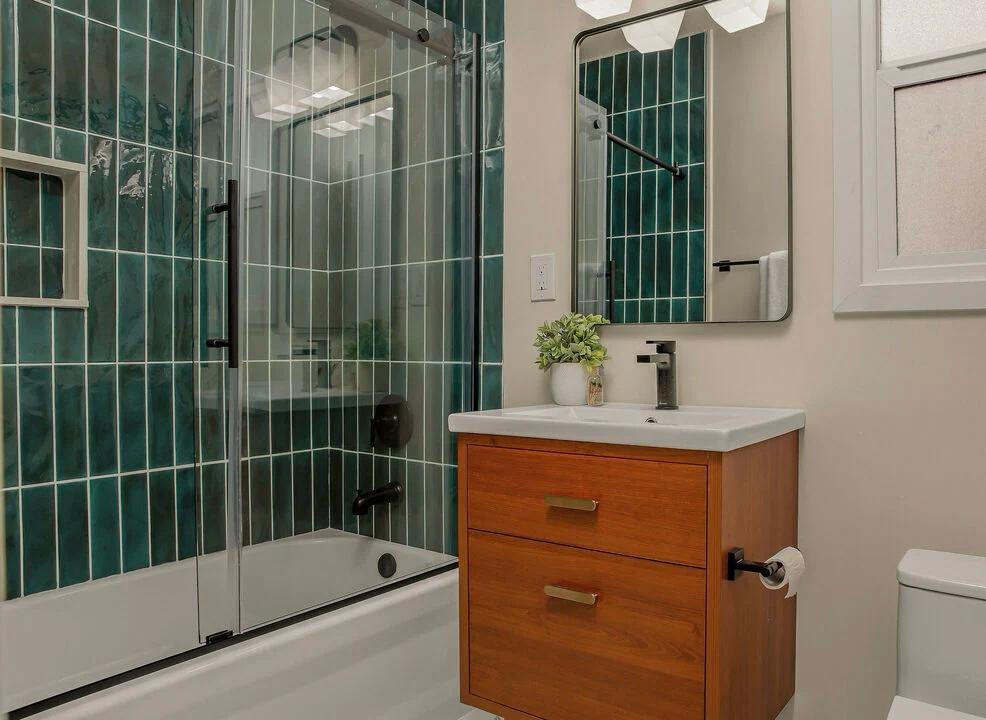 Bathroom with green vertical tile, a glass shower and a wood vanity by Jill Seidner Interior Design