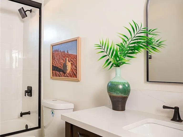 Bathroom vanity with framed art and a green vase by Jill Seidner Interior Design