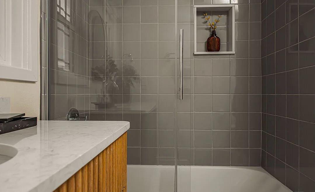 Gray tile walk-in shower beside a wood vanity by Jill Seidner Interior Design
