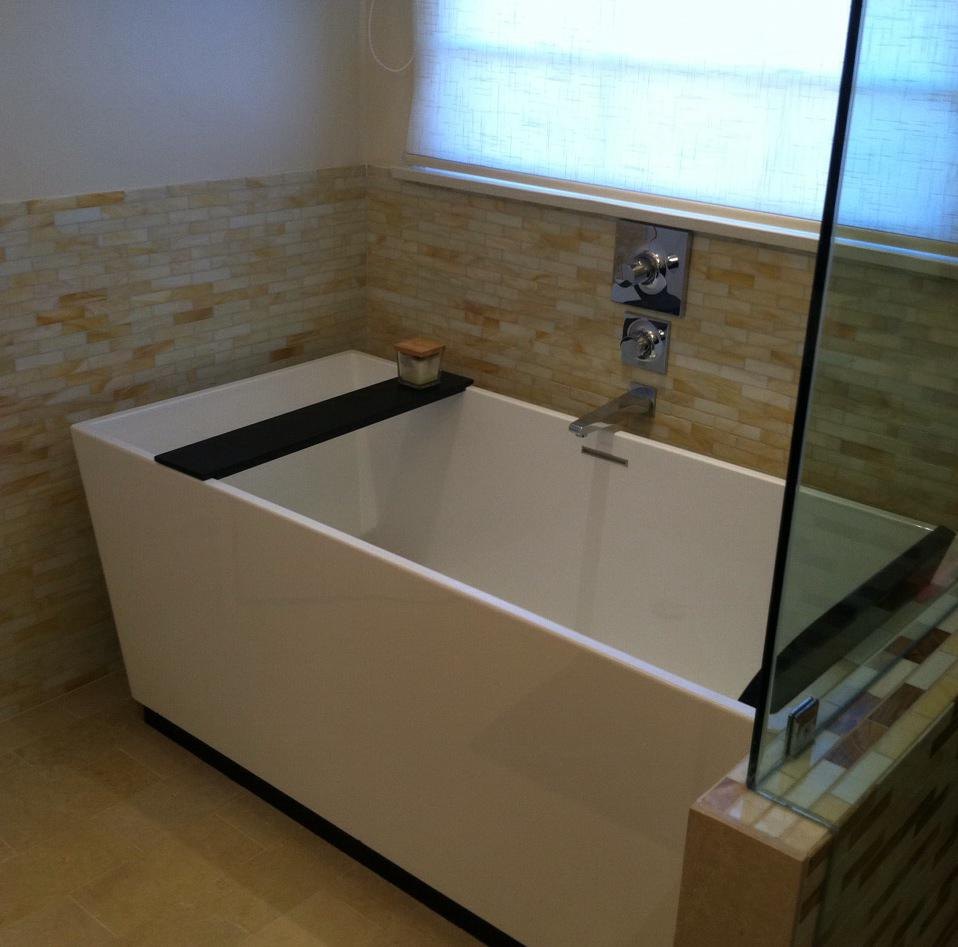 Bathroom with a soaking tub and stone tile by Jill Seidner Interior Design