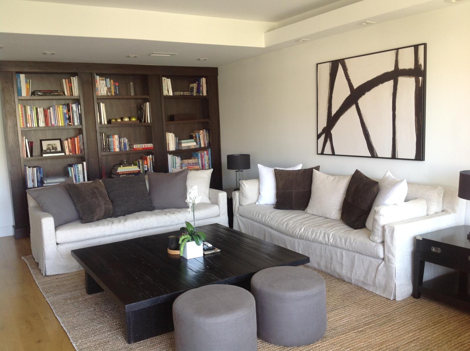 Living room with white sofas, bookshelves and abstract art by Jill Seidner Interior Design
