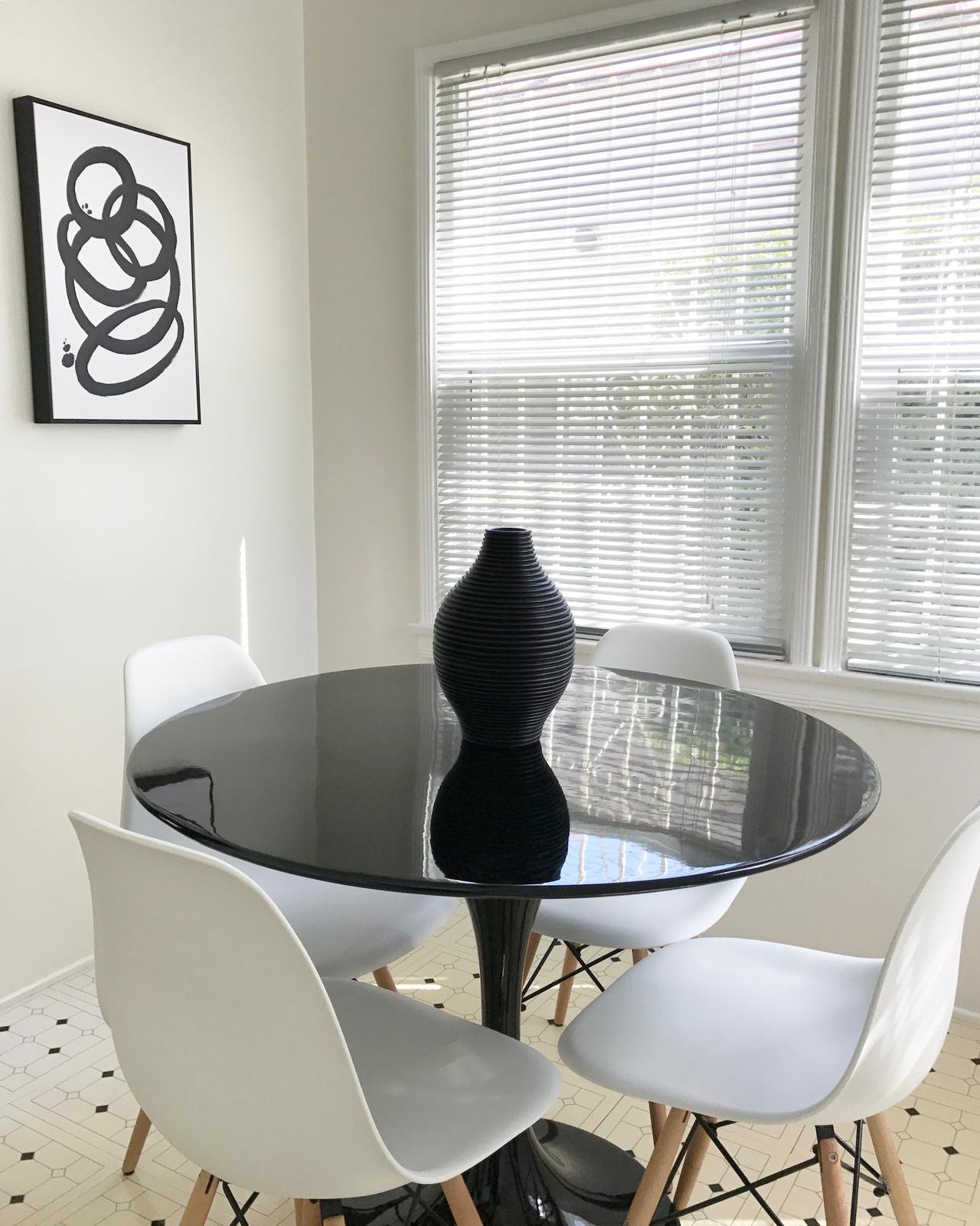 Dining nook with a round black table and white chairs by Jill Seidner Interior Design