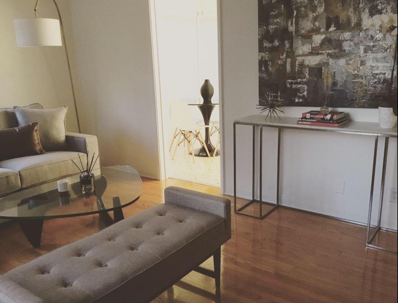 Living room with an upholstered bench, glass coffee table and abstract art by Jill Seidner Interior Design