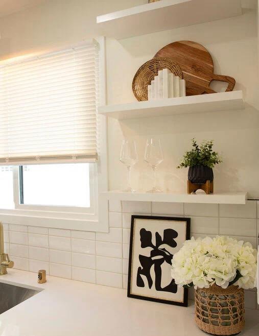 Open kitchen shelves styled with art and a plant by Jill Seidner Interior Design