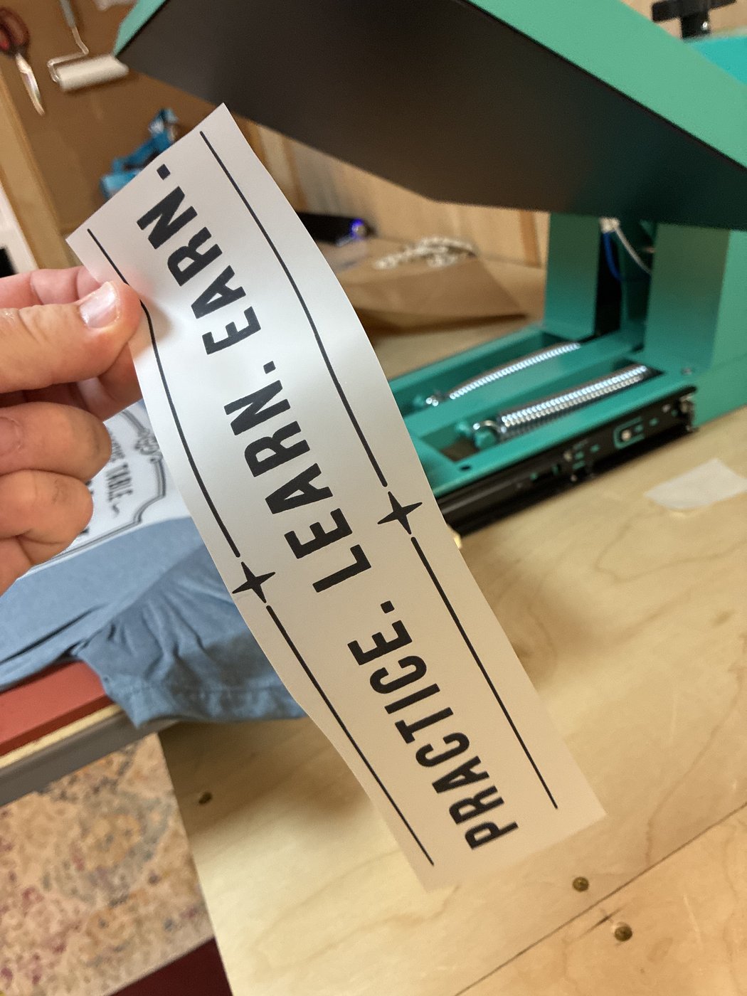 A transfer strip held beside the open press.
