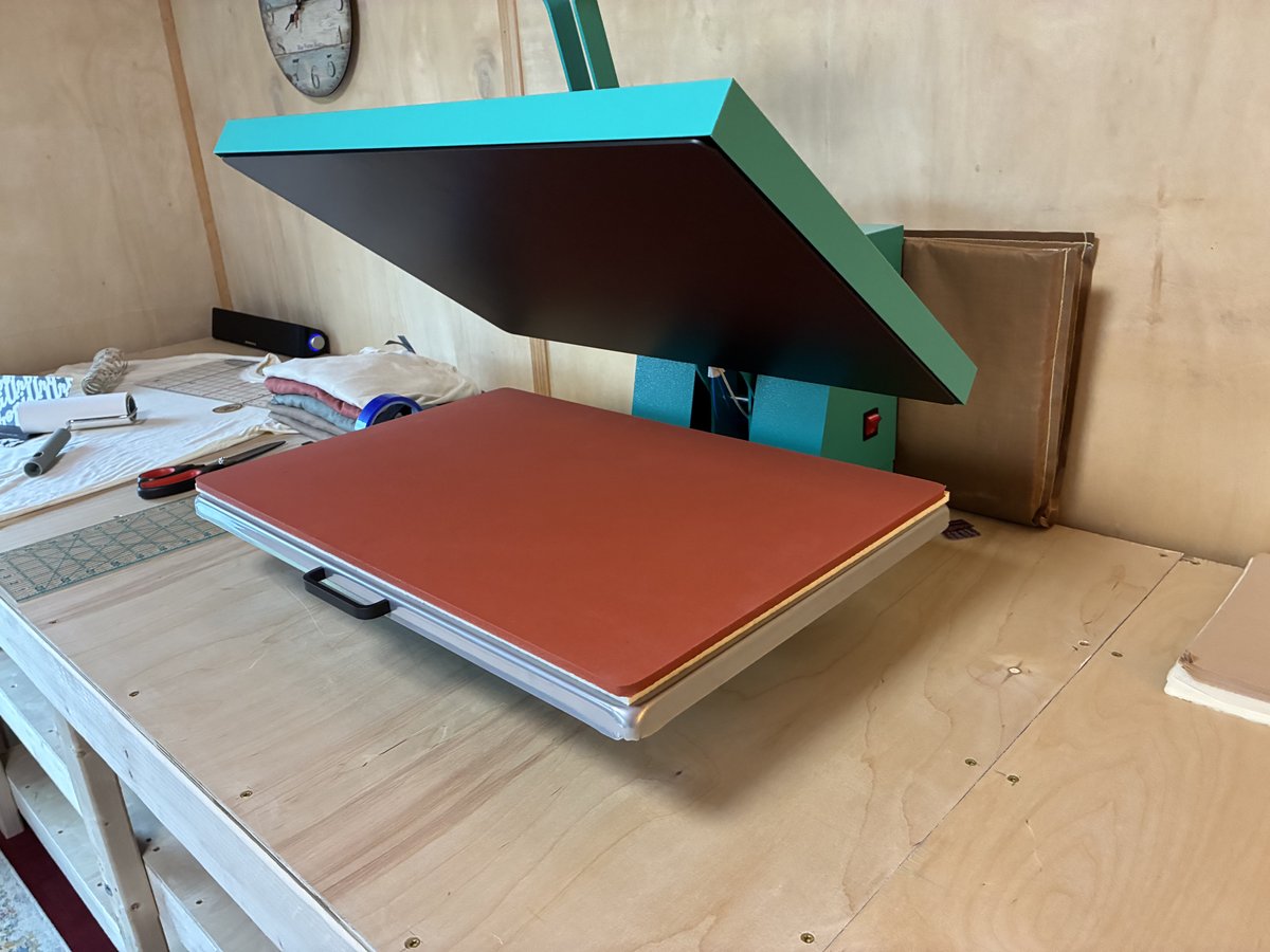 The open heat press on the wooden bench.