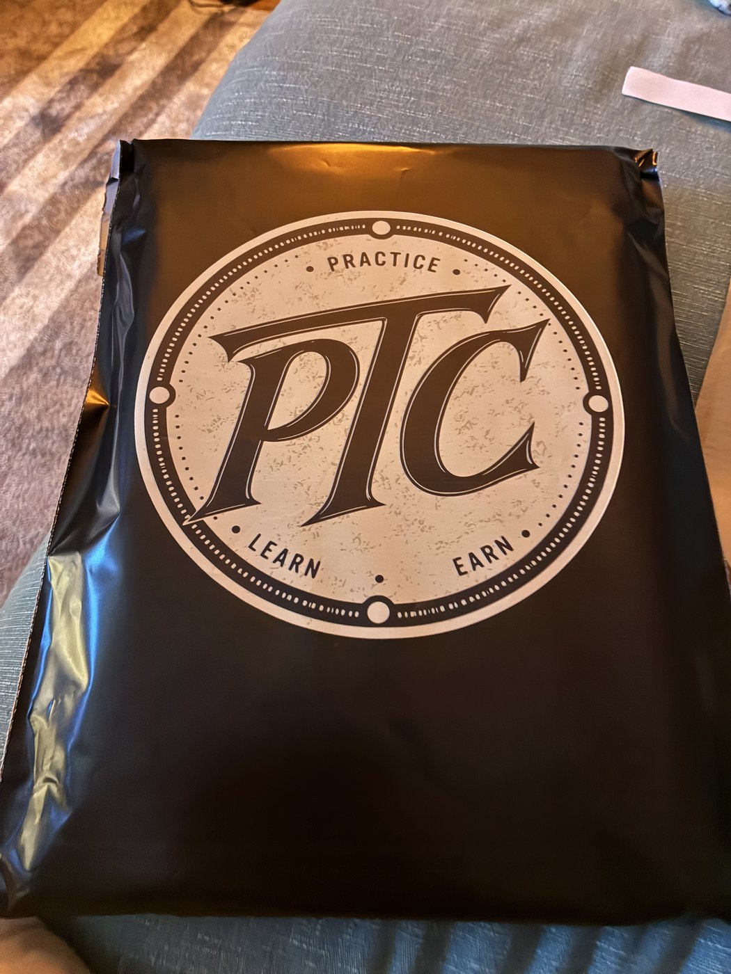 The logo on the front of a black PTC mailer.