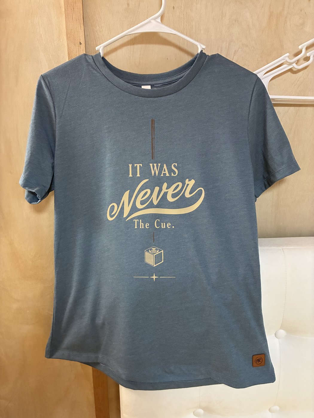The blue-gray “It Was Never The Cue.” shirt in the workshop.