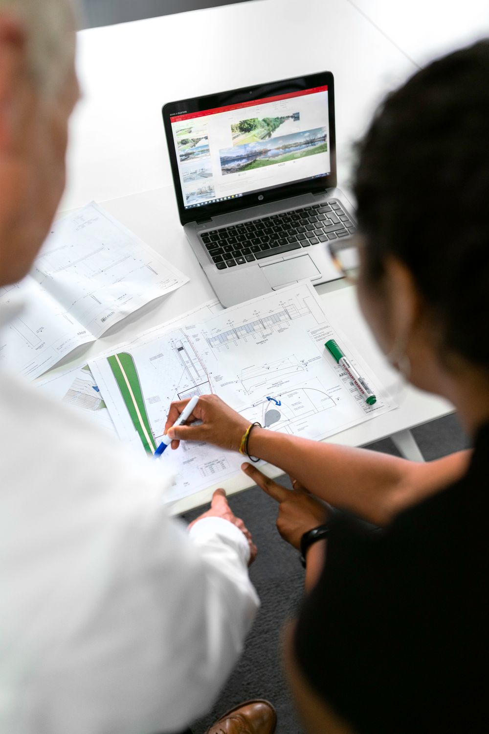 Contractor and bookkeeper reviewing project plans and QuickBooks Online on a laptop