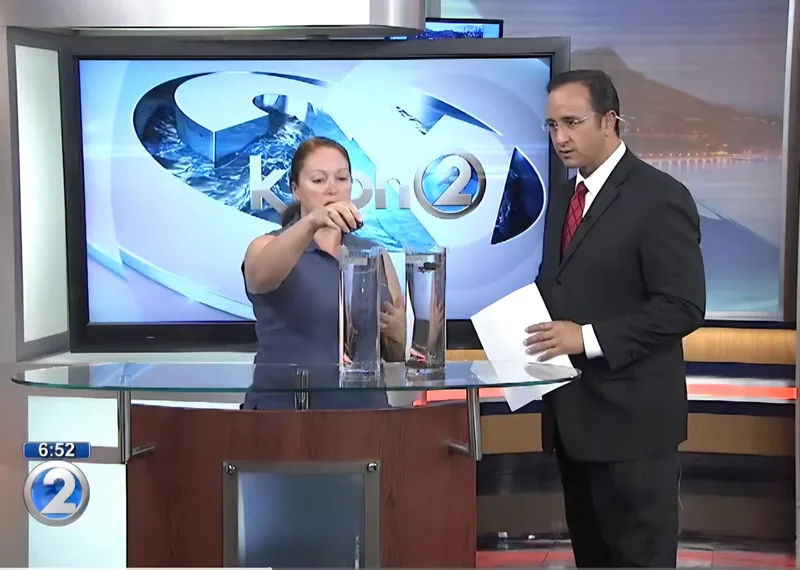 Bernadette Mills demonstrating a science activity with a KHON2 host in the television studio.
