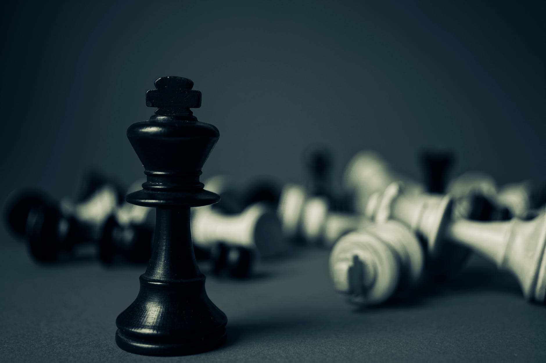 An upright chess king surrounded by toppled chess pieces