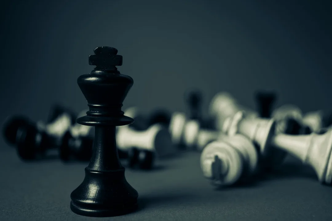 An upright chess king surrounded by toppled chess pieces