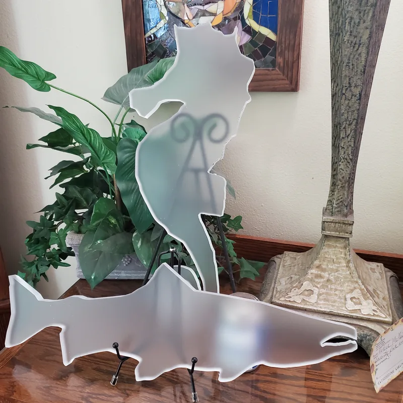 cnc router cut acrylic salmon and seahorse shapes on a shelf