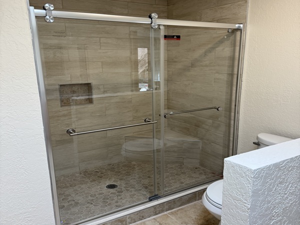 Bathroom shower renovation in Santa Fe, NM area featuring custom shower pan, tiled walls and floor, and new glass shower door