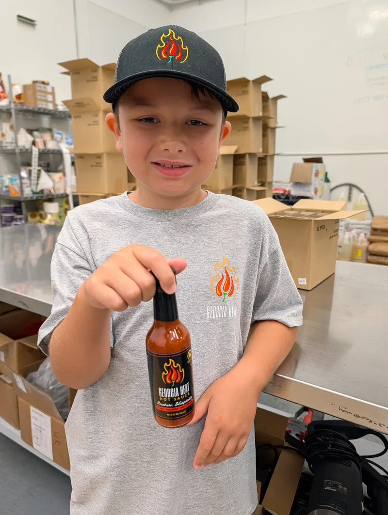 Young man holding hot sauce bottle.