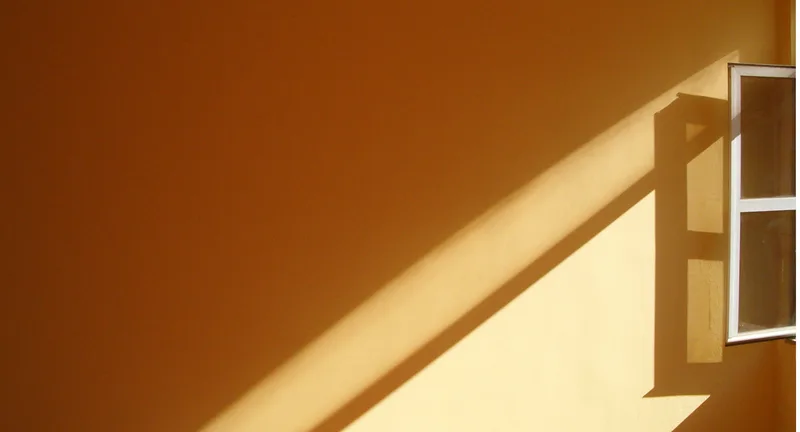 An orange wall with light coming through.