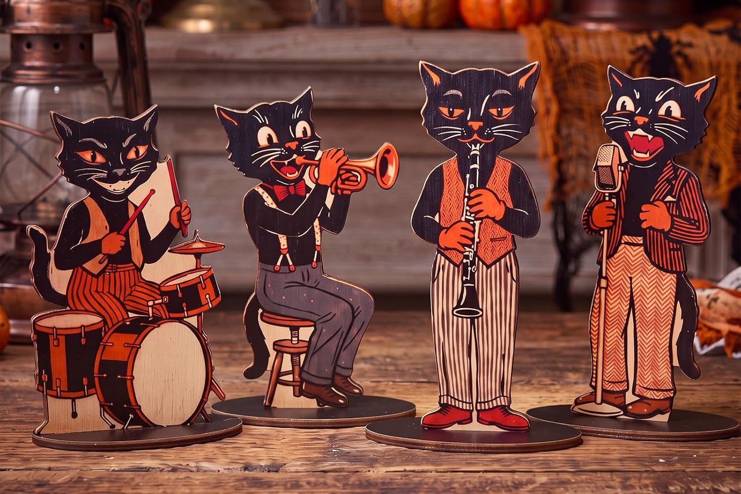 Four vintage-style wooden black cat Halloween decorations playing musical instruments.