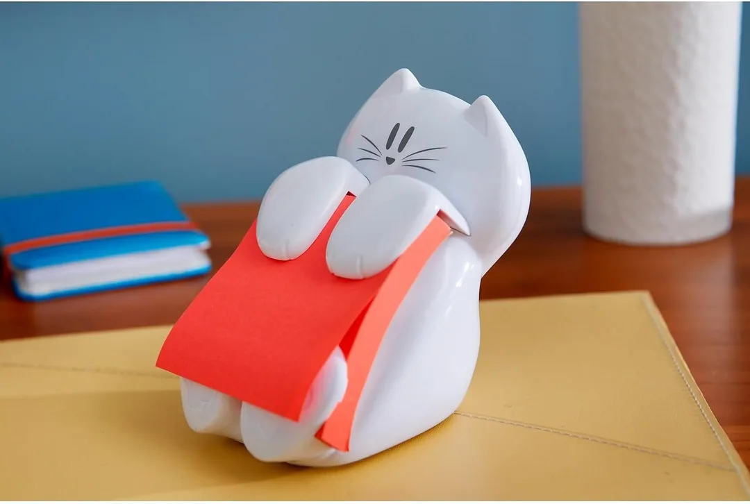 The cat shaped post-it holder sitting on a desk.