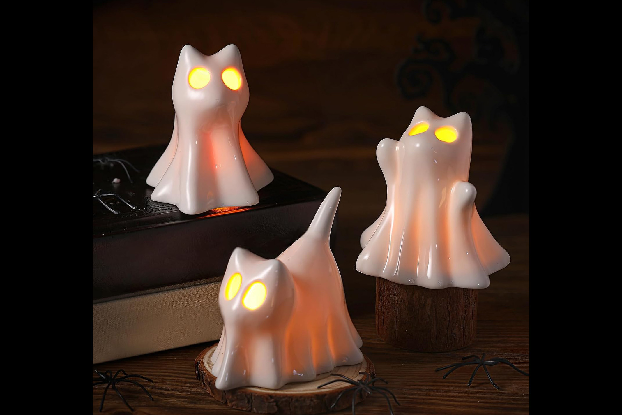 Three ceramic Halloween candle holders shaped like cats dressed as ghosts.