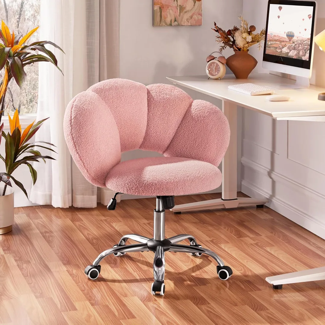 The pink version of the cloud chair sitting at a desk on a hardwood floor.