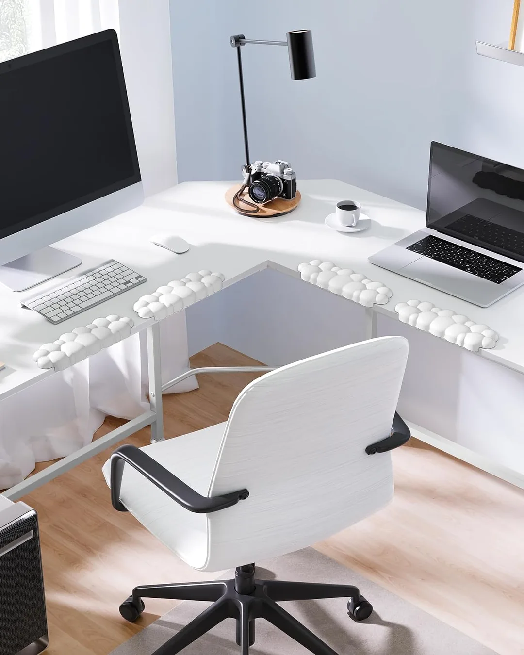 Cloud elbow pads shown on the edge of a white desk in front of a pc setup.